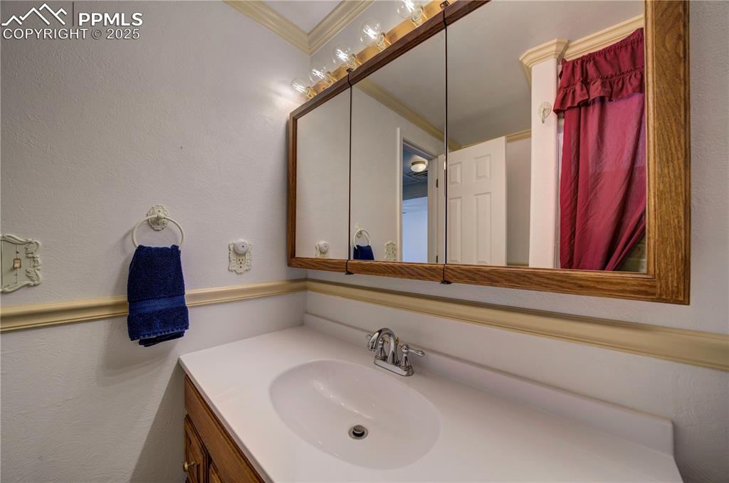 Image 37 of 50: Bathroom with vanity, a textured wall, and ornamental molding