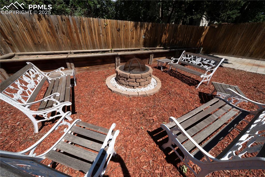 Image 48 of 50: Fenced backyard featuring an outdoor fire pit