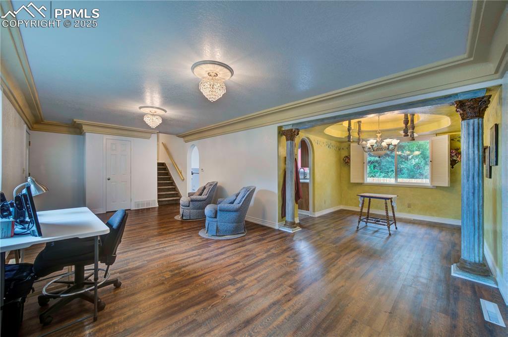 Image 5 of 50: Office featuring dark wood finished floors, decorative columns, a chandelie
