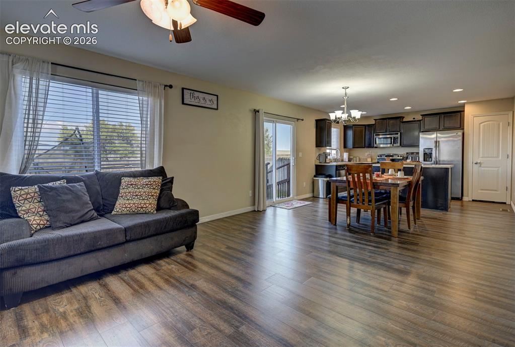 Image 13 of 45: Open-concept living area with wood-finish flooring, a ceiling fan with inte