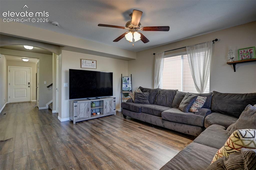 Image 14 of 45: Open living area featuring wood-finish flooring, an arched entryway, and a