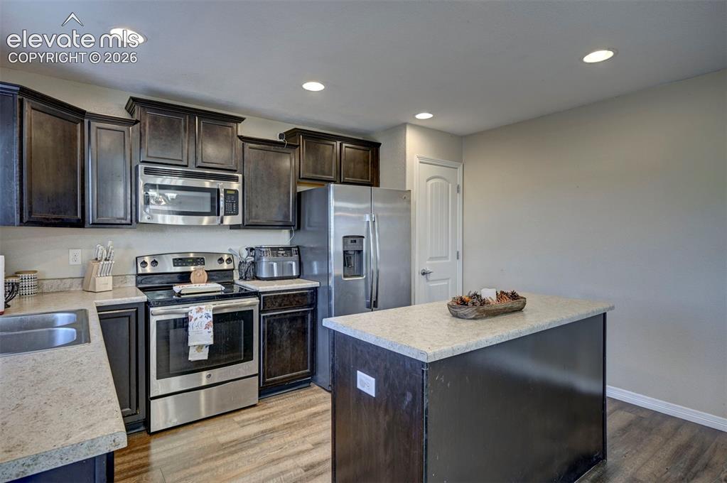 Image 19 of 45: Kitchen featuring dark wood-finish cabinetry, stainless steel appliances, l