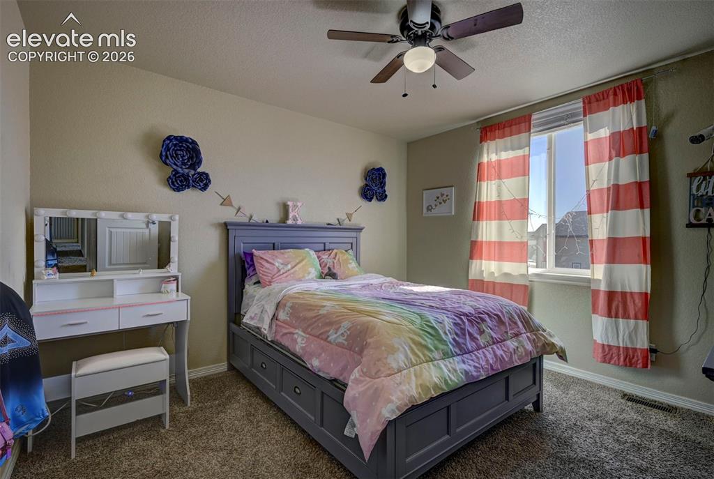 Image 29 of 45: Carpeted bedroom featuring a ceiling fan, a window with a white frame, and