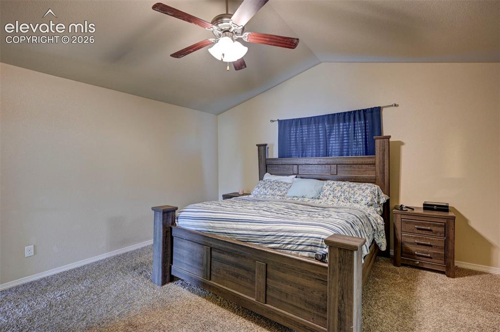 Image 31 of 45: Vaulted ceiling with a wood-finish ceiling fan, neutral wall tones, and car