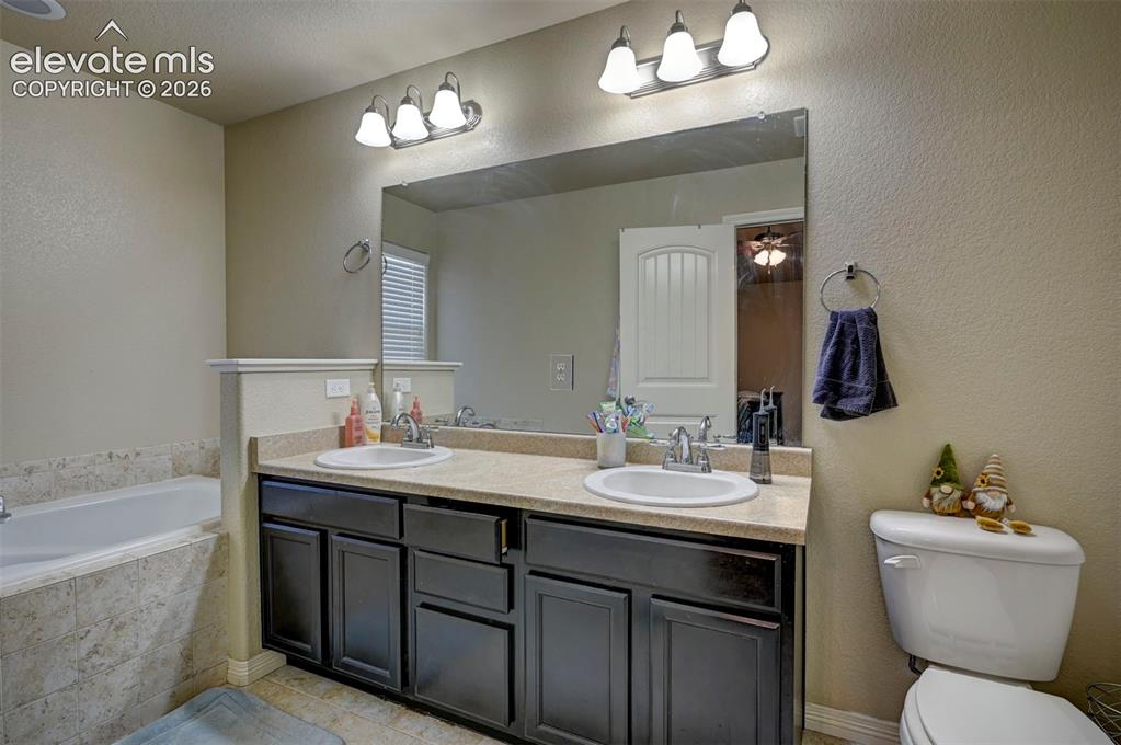 Image 33 of 45: Dual vanity with integrated sinks, a large wall-mounted mirror, and overhea