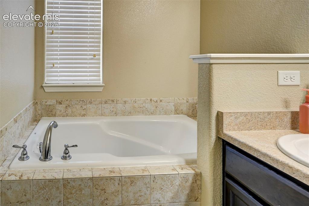 Image 35 of 45: Built-in soaking tub with chrome fixtures, surrounded by neutral-toned tile