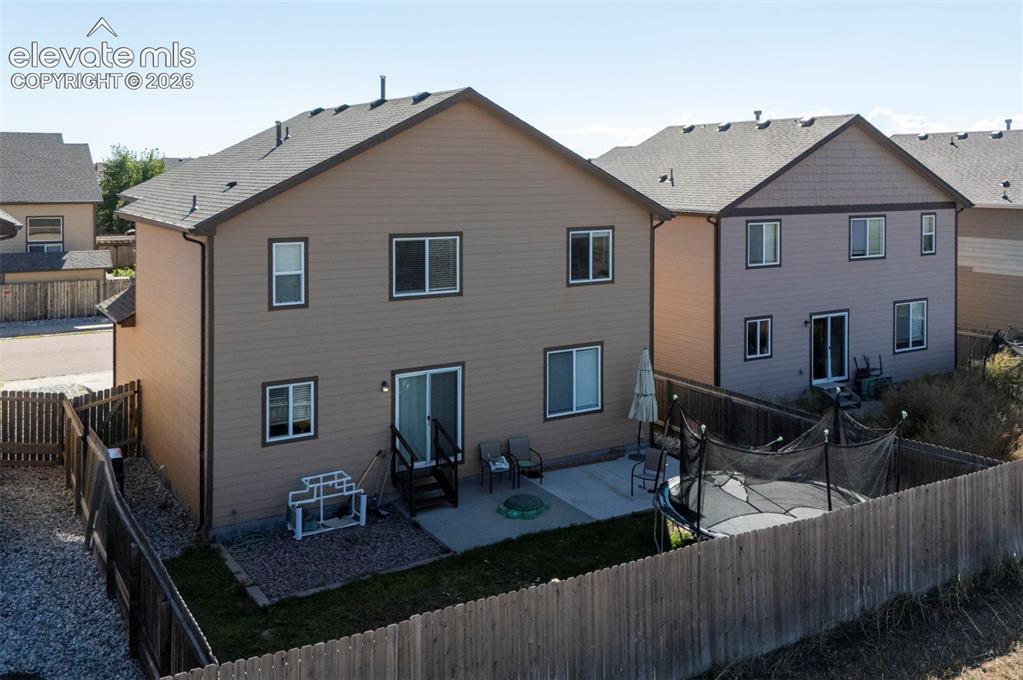Image 39 of 45: Fenced backyard featuring a concrete patio and a sloped, xeriscaped side ya