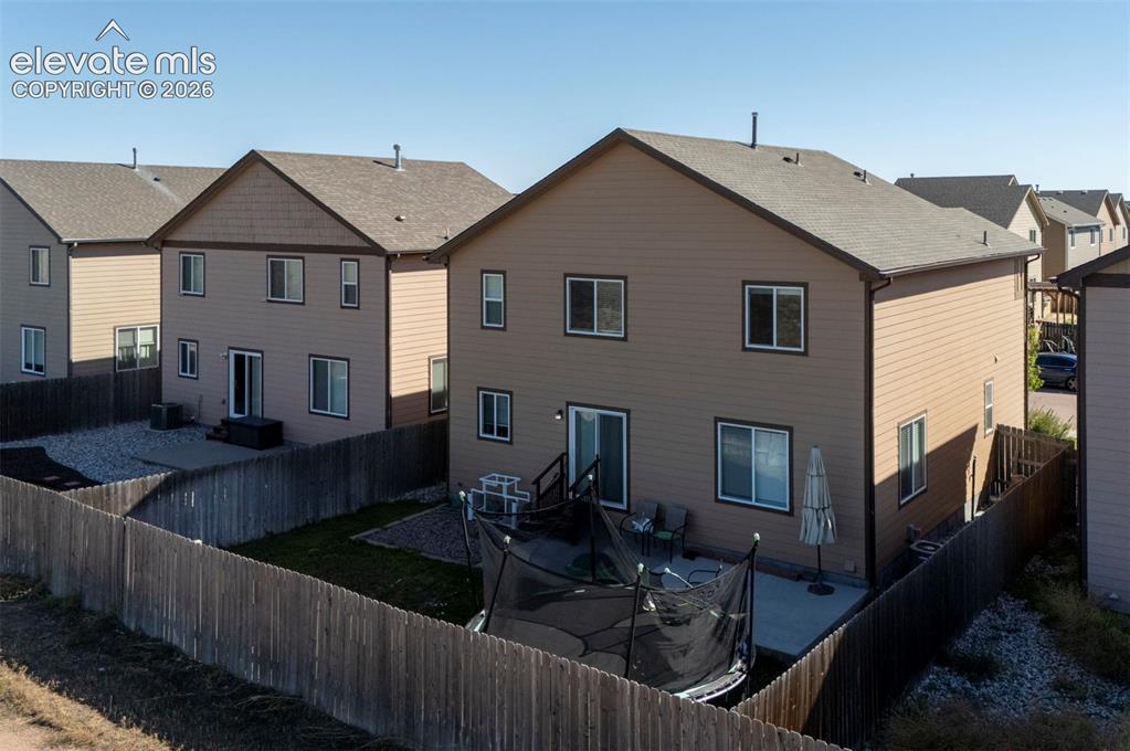 Image 40 of 45: Private rear yard with a concrete patio, wood fencing, and a gravel area