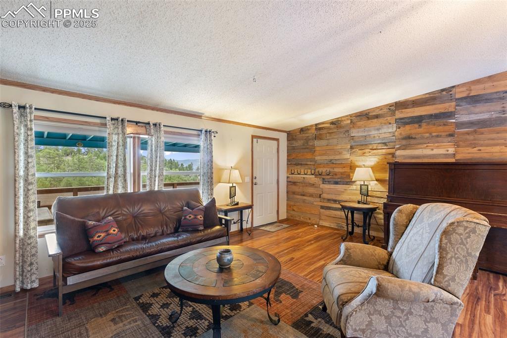 Image 10 of 37: Living room featuring vaulted ceiling, wood laminate floors, ornamental mol