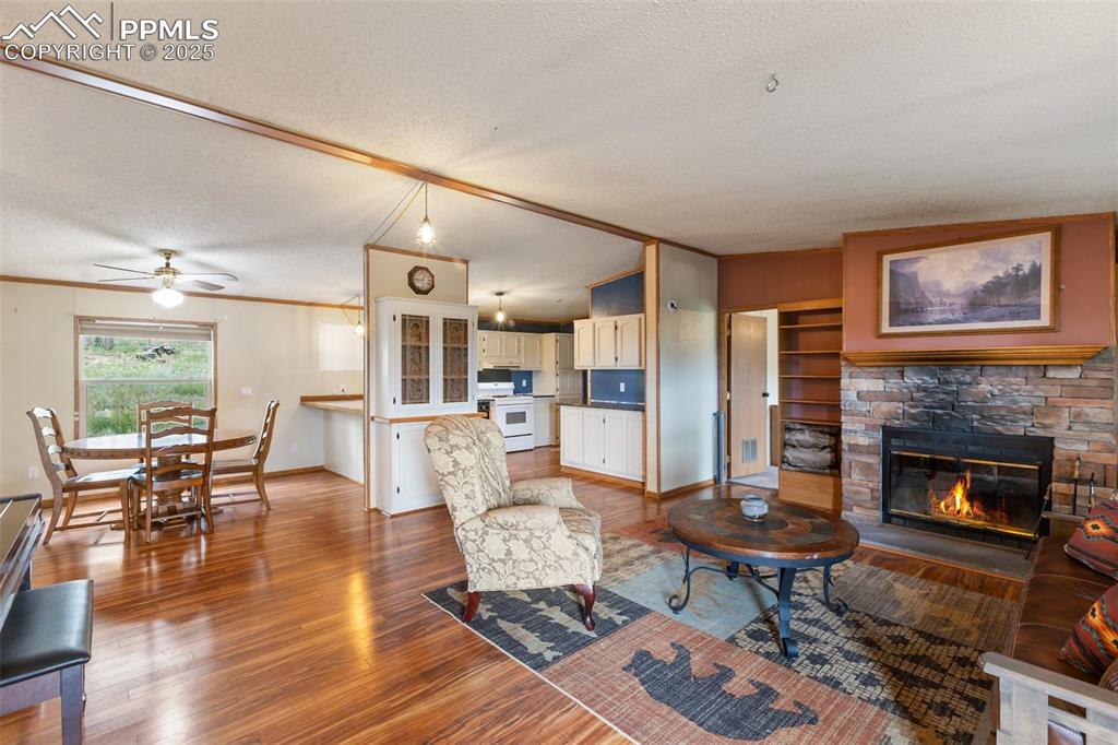 Image 12 of 37: Living room with wood finished floors, a stone fireplace, ornamental moldin