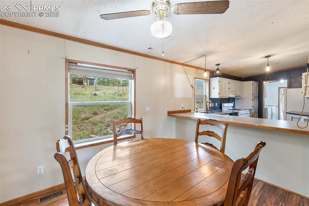 Image 15 of 37: Dining room featuring ornamental molding, wood finished floors, a textured