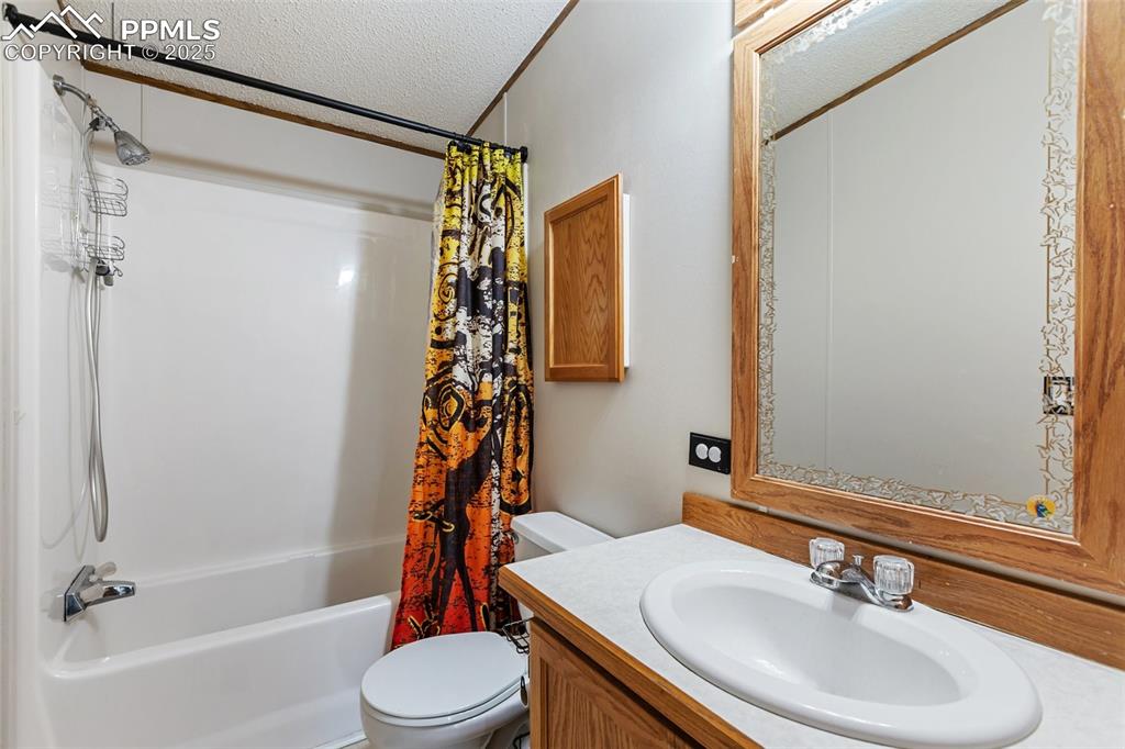 Image 16 of 37: Bathroom with shower / tub combo, a textured ceiling, vanity, and crown mol