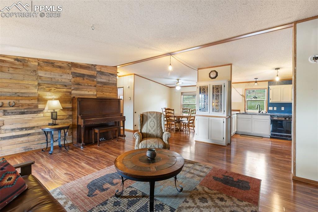 Image 17 of 37: Living room featuring wooden walls, wood finished floors, ornamental moldin