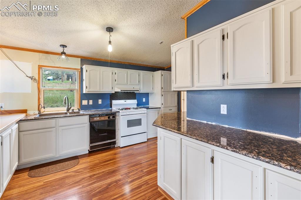 Image 18 of 37: Kitchen featuring white gas stove, white cabinetry, light wood-style floors