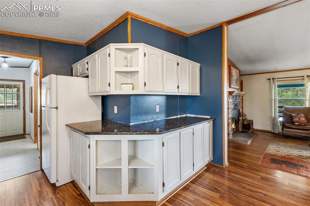 Image 20 of 37: Kitchen with plenty of natural light, open shelves, white cabinets, dark wo