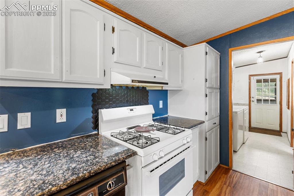 Image 21 of 37: Kitchen featuring white gas range, a textured ceiling, washing machine and