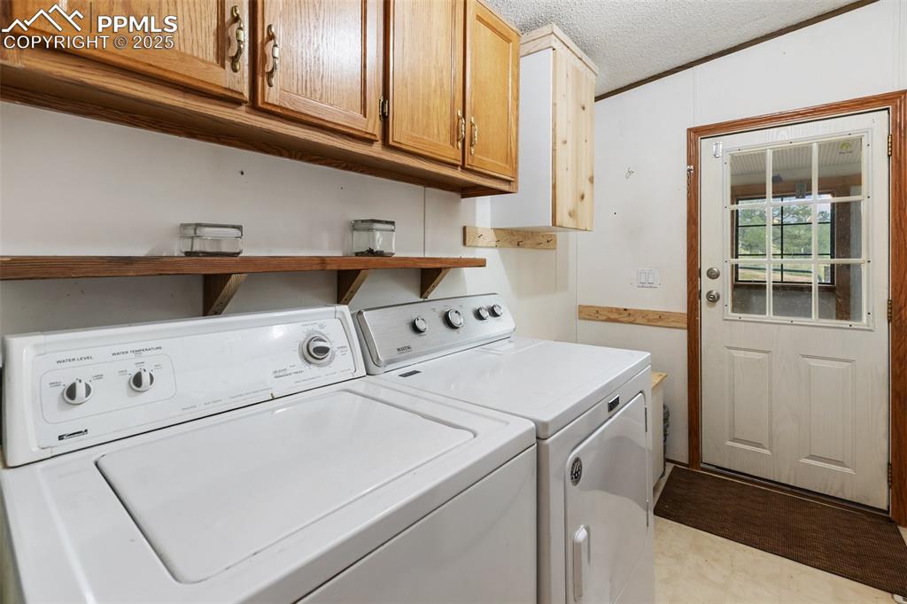 Image 29 of 37: Washroom with a textured ceiling, washer and clothes dryer, cabinet space,