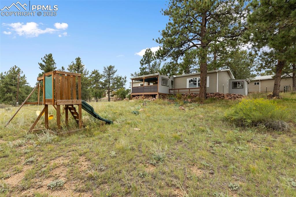 Image 6 of 37: View of yard featuring a playground and a wooden deck