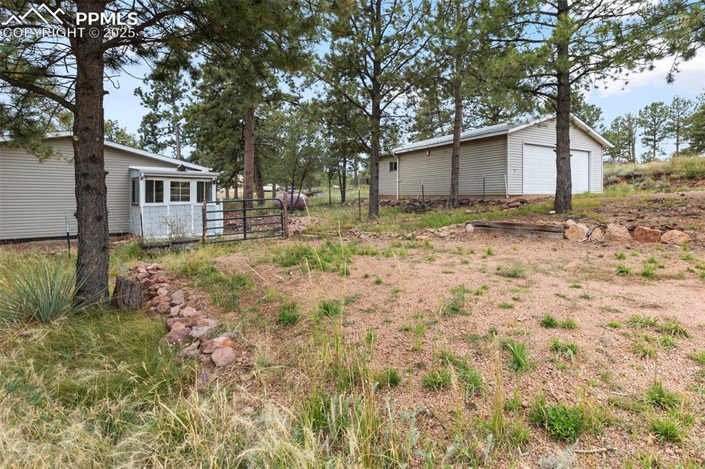 Image 9 of 37: View of yard with a detached garage and parking areas on side of the home b