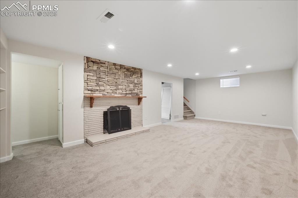 Image 12 of 22: Below grade area featuring light carpet, a stone fireplace, recessed lighti