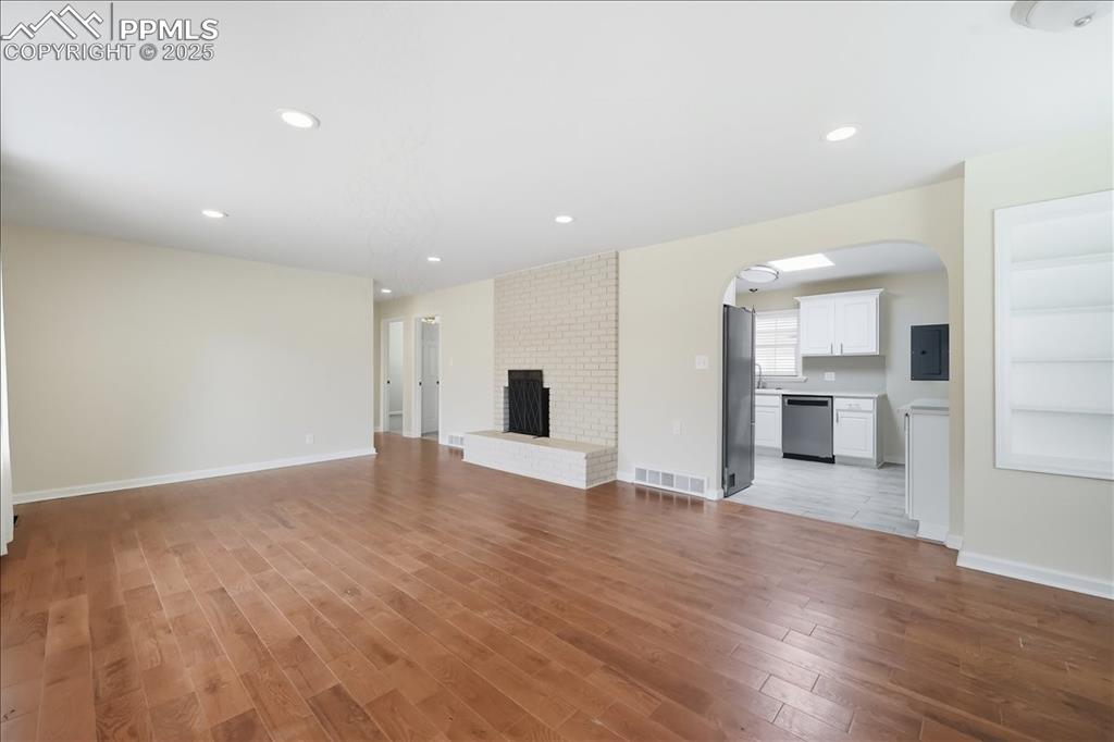 Image 2 of 22: Unfurnished living room featuring arched walkways, recessed lighting, light
