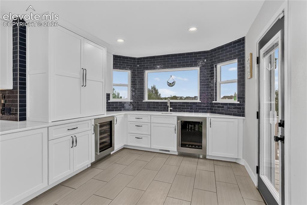 Image 8 of 29: Walk-out wet bar w/ dual wine fridges