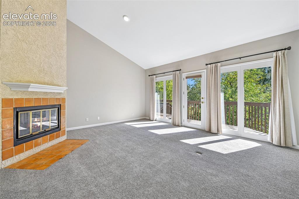 Image 10 of 46: Living area featuring a vaulted ceiling, a floor-to-ceiling fireplace with 