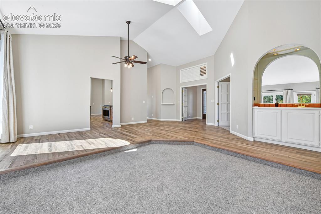 Image 12 of 46: Living area featuring vaulted ceilings with skylights, sunken carpeted floo
