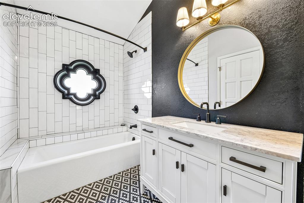 Image 15 of 46: Bathroom featuring a white shaker-style vanity with stone-look countertop,