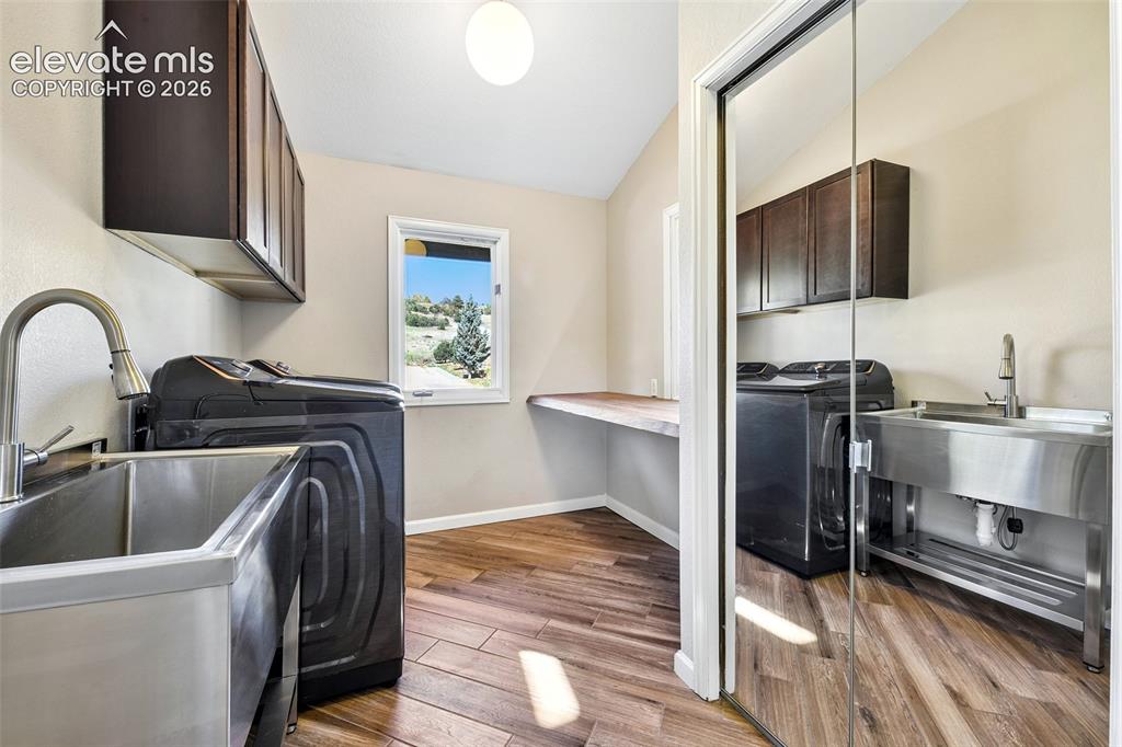 Image 16 of 46: Laundry room featuring wood-finish flooring, stainless steel utility sinks 