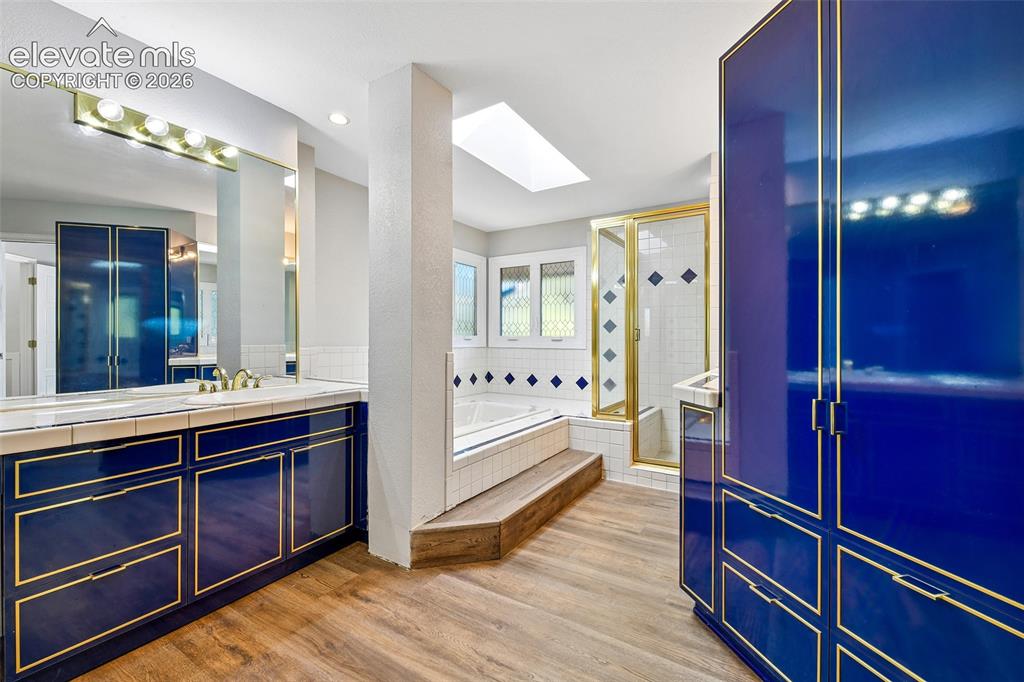 Image 18 of 46: Glossy deep-blue cabinetry with gold-toned trim, wood-finish flooring, a bu