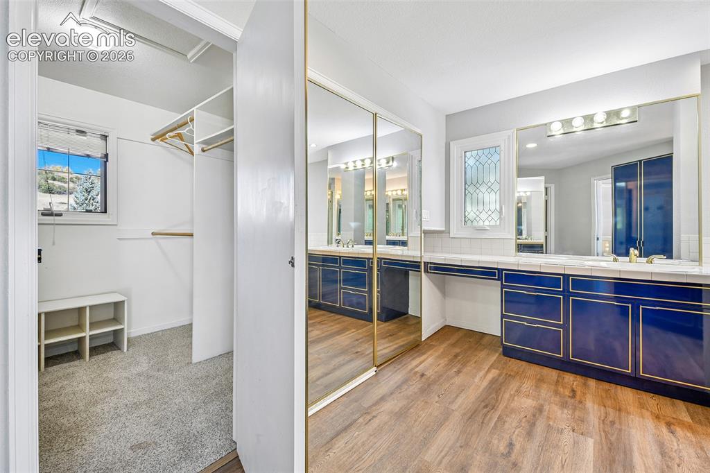 Image 19 of 46: Custom blue cabinetry featuring gold-tone trim, expansive wall-to-wall mirr