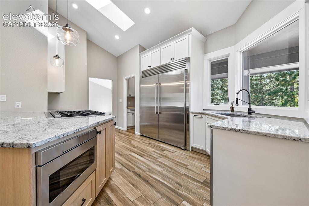Image 21 of 46: Kitchen featuring stone countertops, stainless steel side-by-side refrigera