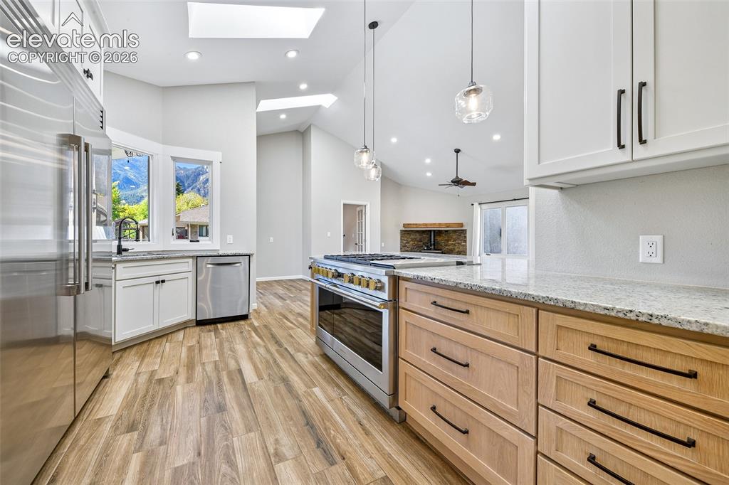 Image 22 of 46: Kitchen featuring vaulted ceilings, skylights, wood-finish flooring, stainl