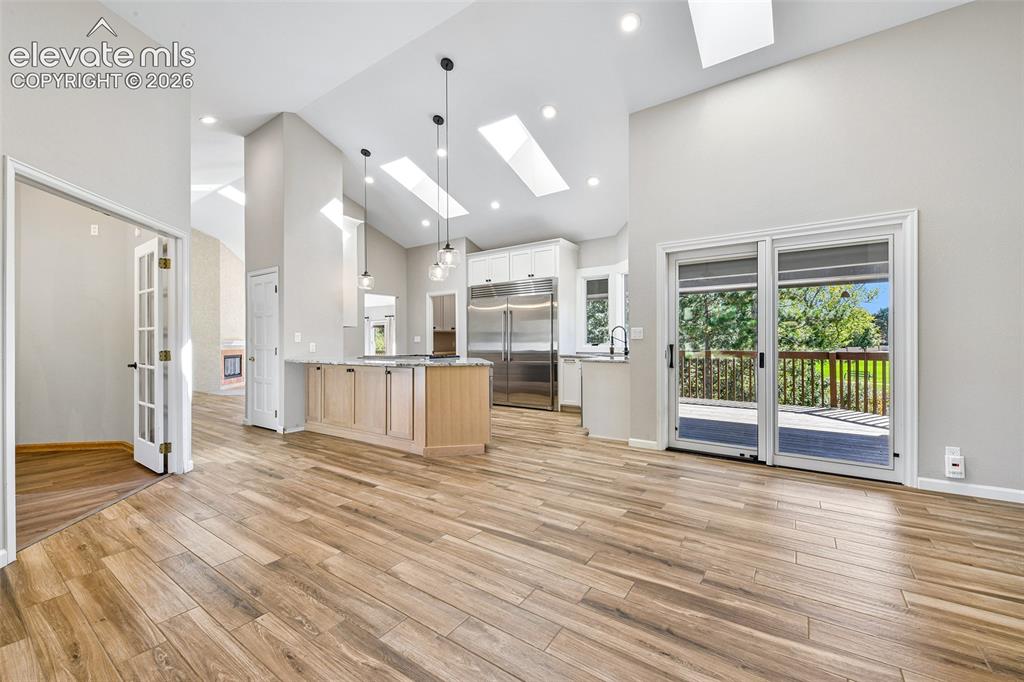 Image 26 of 46: Vaulted ceilings featuring multiple skylights, wood-finish flooring, a kitc