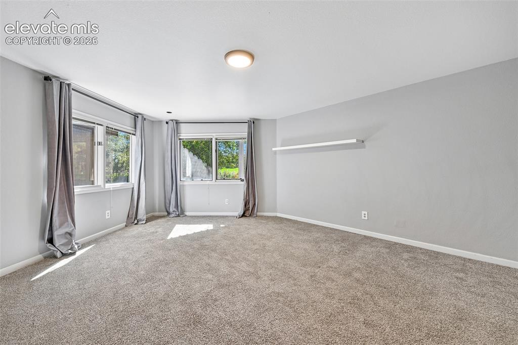 Image 28 of 46: Neutral-toned room featuring wall-to-wall carpeting, dual windows, and a wa