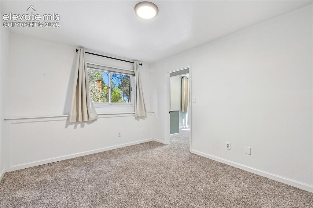 Image 29 of 46: Interior room featuring neutral-toned carpeting, white wainscoting, a singl