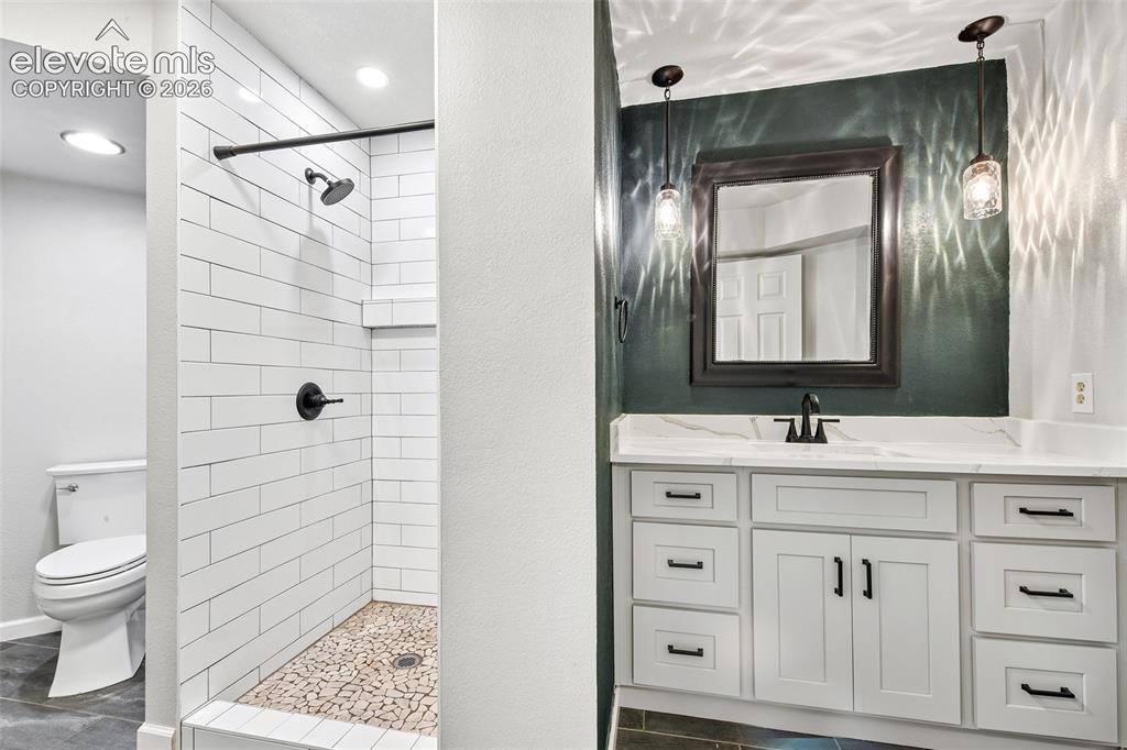 Image 30 of 46: Bathroom featuring a vanity with stone-top surfacing, white cabinetry with