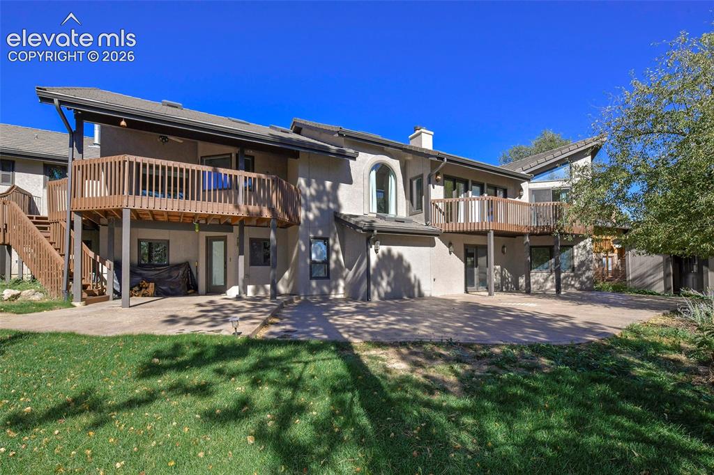 Image 38 of 46: Stucco exterior featuring dual-level wood-railing decks, a concrete patio, 