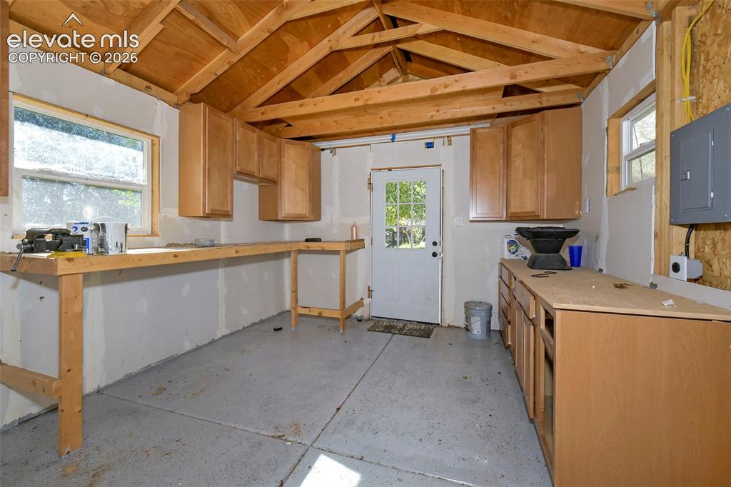 Image 43 of 46: Utility space featuring exposed wood-truss ceiling, built-in wooden cabinet
