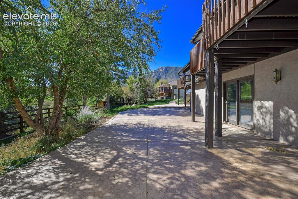 Image 5 of 46: Stamped concrete patio with a tiered wood-railing deck, exterior wall-mount
