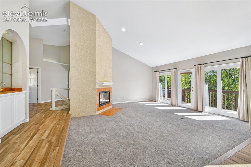 Image 9 of 46: Vaulted ceilings with recessed lighting, double-sided central fireplace fea