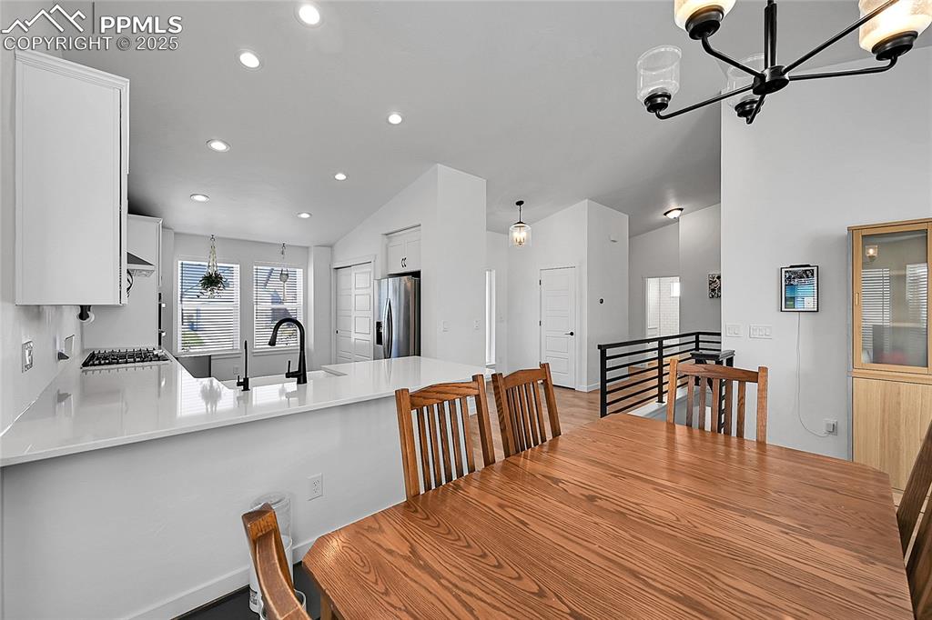 Image 10 of 29: Dining area with a chandelier, vaulted ceiling, and recessed lighting