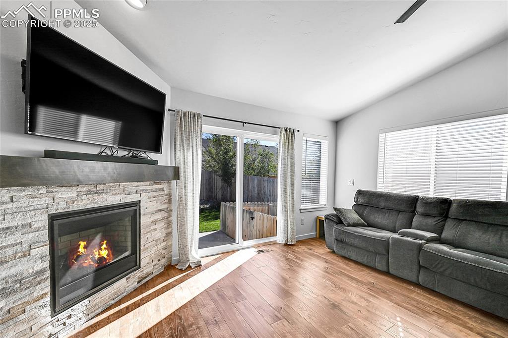 Image 12 of 29: Living area with vaulted ceiling, hardwood / wood-style flooring, a stone f