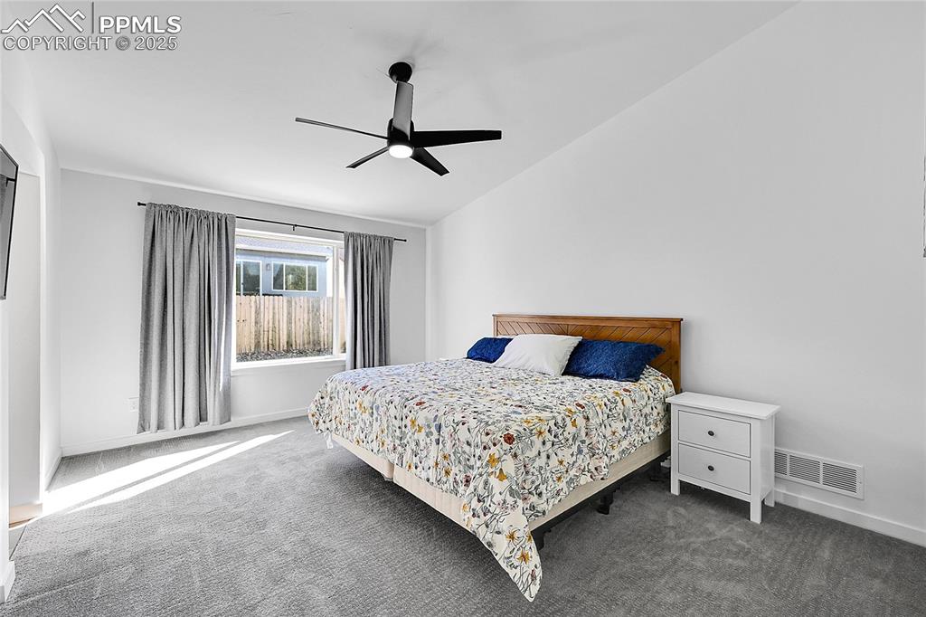 Image 18 of 29: Carpeted bedroom with lofted ceiling and ceiling fan
