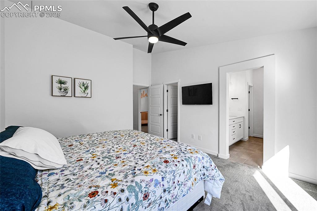 Image 19 of 29: Bedroom featuring light colored carpet, a ceiling fan, and connected bathro