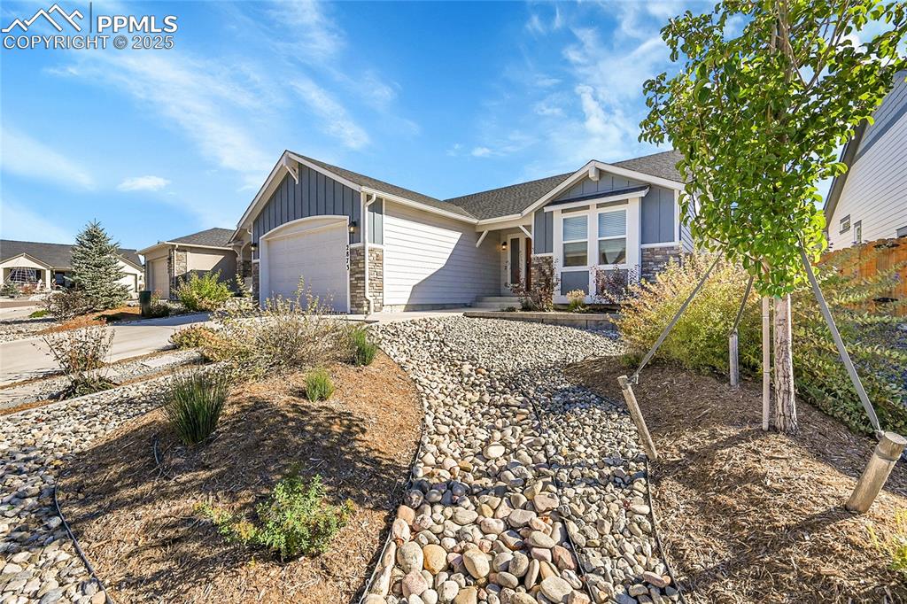 Image 2 of 29: Craftsman house featuring board and batten siding, an attached garage, ston