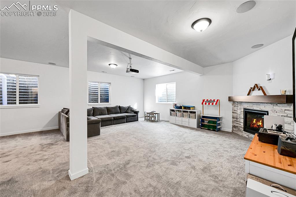 Image 24 of 29: Living room featuring light carpet and a stone fireplace