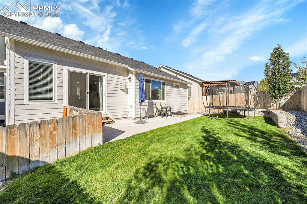 Image 29 of 29: Back of property featuring a trampoline, a fenced backyard, a patio, and a 