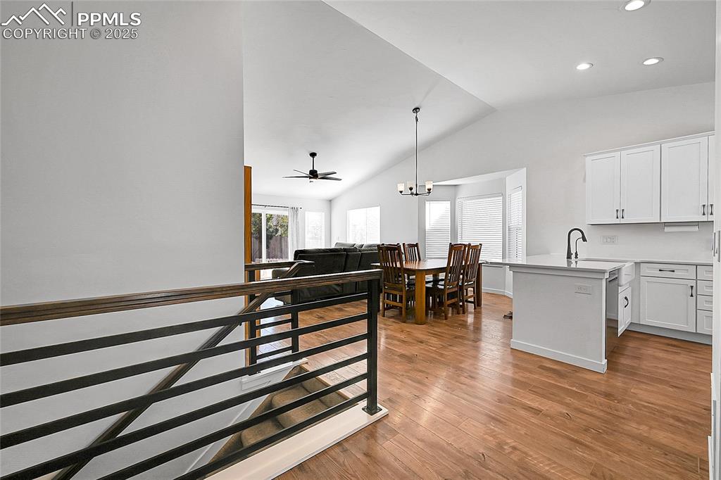 Image 4 of 29: Staircase with lofted ceiling, wood finished floors, a chandelier, recessed